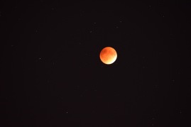 Red Moon glowing in an otherwise dark sky